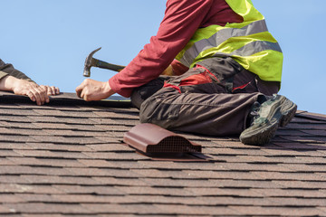 Workman install element of tile roof on new home under construction