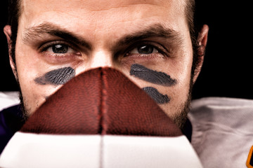 Portrait of american football player holding a ball and looking at camera