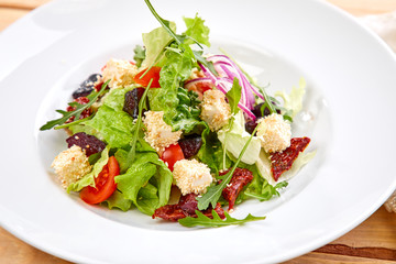 vegetarian salad with dried tomatoes and croutons on the wooden background