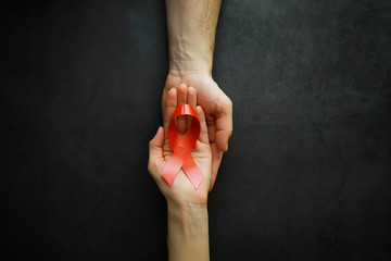 Symbol of human immunodeficiency virus disease. Red ribbon. A helping hand and support.