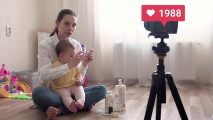 Young pretty mother with baby recording vlog or doing live stream and going virel with liked counter 4k