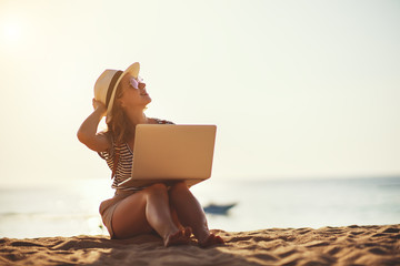 young woman working with laptop on nature in beach.