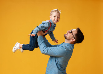 happy father's day! cute dad and son hugging on yellow background