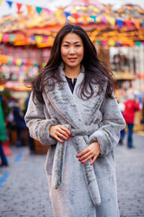 Happy asian woman in winter coat from faux fur