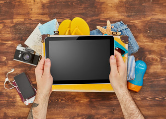Man holding a digital tablet and packing for vacation