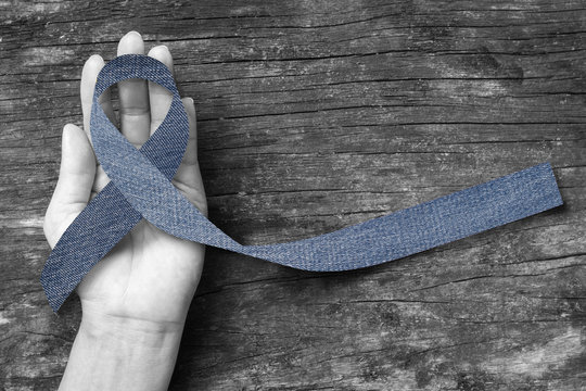 Blue Jeans Denim Ribbon (isolated With Clipping Path) On Helping Hand Support And Aged Wood For Genetic Disorder Awareness And Children's Rare Disease Illness