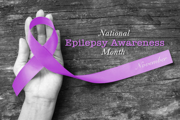 National Epilepsy Awareness Month in November by Lavender ribbon on hand, aged wood background