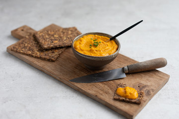Sweet potato or pumpkin or carrot hummus with parsley and olive oil, served with seed crackers on a...