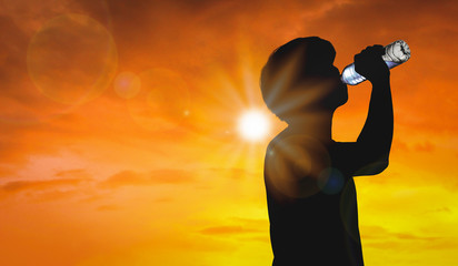 Silhouette man is drinking water bottle on hot weather background with summer season. High...