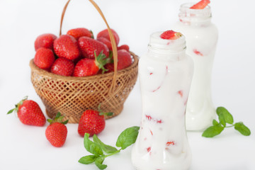 Strawberry smoothie or milkshake with fresh berries and mint in ittle bottles on white background. Healthy food and drinks.