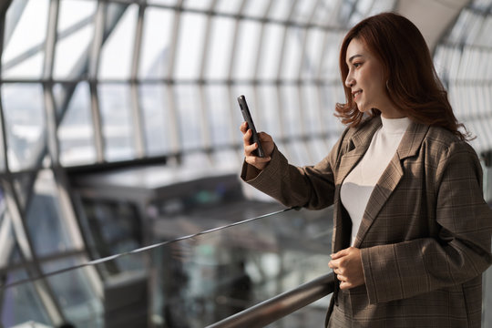 beautiful woman waiting for flight and using smart phone in airport