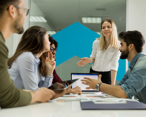Pretty female team leader talking with mixed race group of people in the office