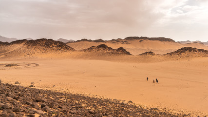 Travellers walking in a sacred valley in Sahara Desert, Algeria
