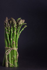Bunch of fresh asparagus on black background, free space for text