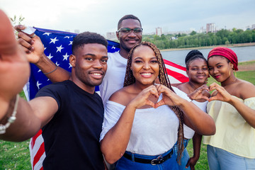 Group of girls and boys smiling with American flag in spring park autumn evening learning English...