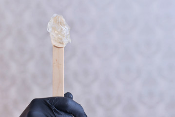 epilation and beauty concept - procedure of hair removing on leg beautiful woman with sugar paste or wax honey and black gloves hand