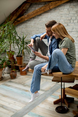 Obraz premium Young couple is using a digital tablet and smiling in kitchen at home