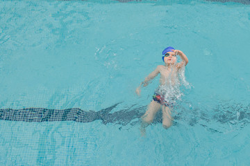 top view of a 7-year boy swimming backstroke in a swimming pool