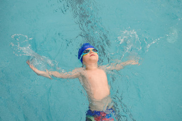 top view of a 7-year boy swimming backstroke in a swimming pool