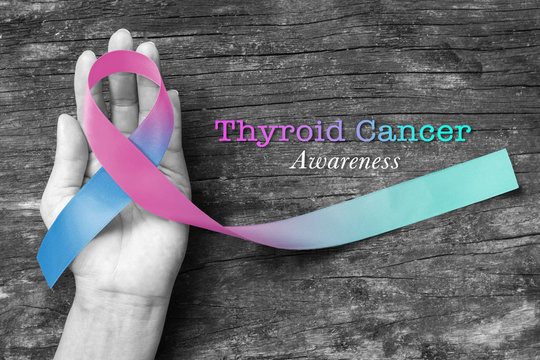 Thyroid Cancer Awareness ribbon Teal Pink Blue color ribbon on woman helping hand support on old aged wood background (isolated with clipping path)