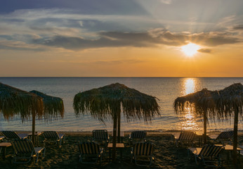 empty beach with thatched umbrellas and sun loungers in the mornings in summer
