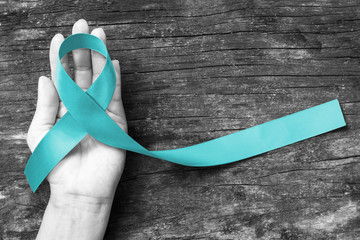 Teal ribbon awareness on woman's hand for Ovarian Cancer, Polycystic Ovary Syndrome (PCOS) disease,...
