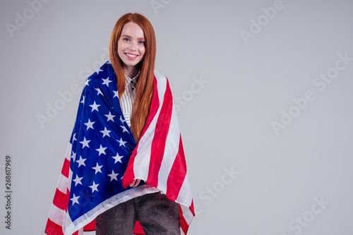 happy young and beautiful redheaded businesswoman holding American flag on white background in studio : independence day usa 4th of july,English language learning