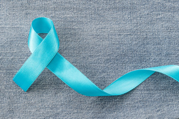 Blue ribbon symbolic of prostate cancer awareness campaign and men's health in November month on Jeans denim