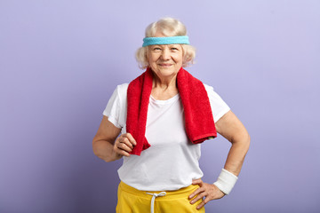 Healthy active retired woman in sports wear and red towel on neck, looking at camera with beaming face, celebrating personal track records. © alfa27