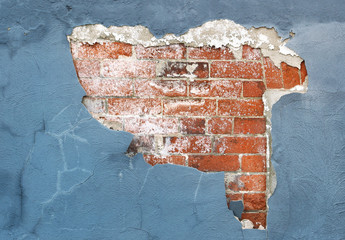 Brick wall with peeling paint and plaster in need of repair