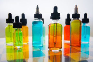 Vape concept. Beautiful colorful vape liquid glass bottles outdoor on stones. Useful as background or electronic cigarette advertisement.