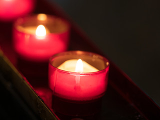close up of a prayer candle lit in a red container