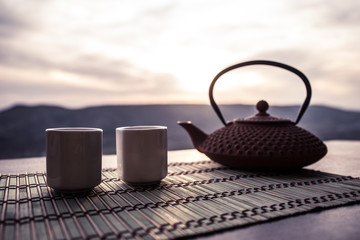 Tea concept. Japanese tea ceremony culture east beverage. Teapot and cups on table with bamboo leaves on sunset
