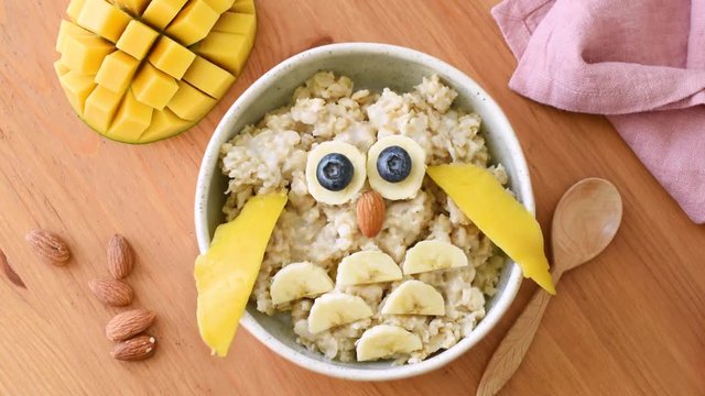 Healthy oatmeal porridge in bowl with funny owl face, champion breakfast for kids. Stop motion animation