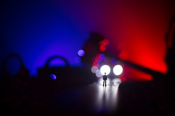 Fototapeta na wymiar Legal law concept. Silhouette of handcuffs with The Statue of Justice on backside with the flashing red and blue police lights at foggy background. Selective focus