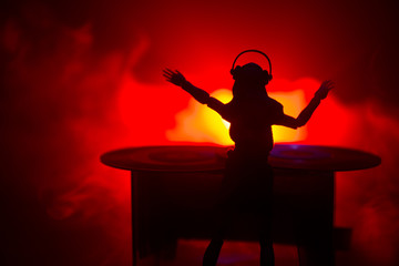 Dj club concept. Woman DJ mixing, and Scratching in a Night Club. Girl silhouette on dj's deck,...