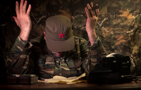 The evil dictator sitting on table. Angry communist general sitting at headquarter or Cuban commander in dark room.