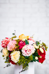 close up of summer flowers in round box over white wall background with copy space