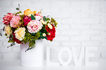 summer flowers in round box and word love over white wall background
