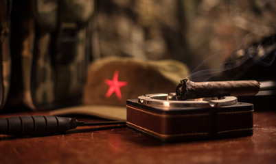 Close up of a Cuban cigar and ashtray on the wooden table. Communist dictator commander table in...