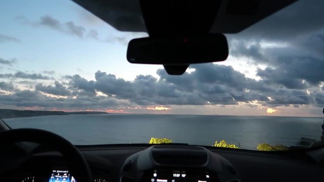 ocean view through the windshield of a car that stopped at the edge of a cliff