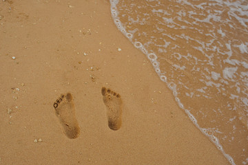 Footprints of human feet on the sand near the water on the beach