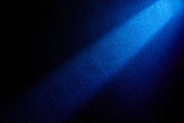 Dark blue beam of light shining from top to bottom on a dark background.
