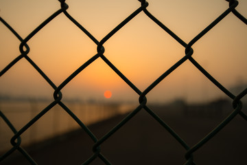 フェンスの向こうの夕暮れ風景