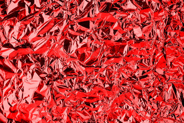Crumpled red foil shining texture background, bright shiny festive design, metallic glitter surface, holiday decoration backdrop concept, metal shimmer light effect, sparkling red color pattern