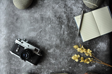 Gray abstraction background table for site. Details on the table: Notepad, pen, camera, dry flowers. Background traveler and photographer.