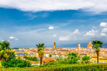 Top aerial panoramic view of Florence city with Duomo Santa Maria del Fiore cathedral, Ponte Vecchio bridge, buildings with orange red tiled roofs, Arno river, blue sky white clouds, Tuscany, Italy