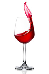Red wine splashing out of wineglass isolated on white background.