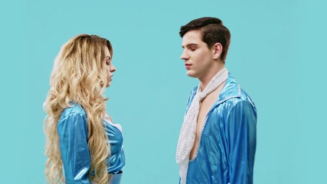A pair of blue costumes on a blue background dance a strange dance blinking eyes in the camera. Sex dance LGBT