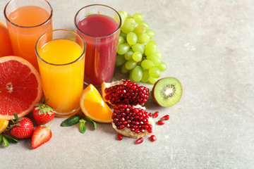 Glasses of different juices and fresh fruits on table. Space for text